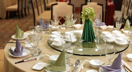 a long table with plates and wine glasses and flowers at SUN Yat-sen university Hotel and Conference Centre in Guangzhou