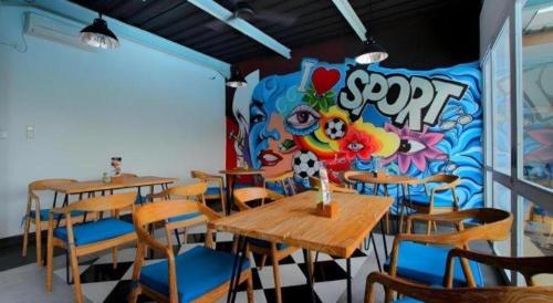 a restaurant with tables and chairs and a colorful wall at Umah Bali Suites in Denpasar