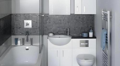 a white bathroom with a sink and a toilet at Umah Bali Suites in Denpasar