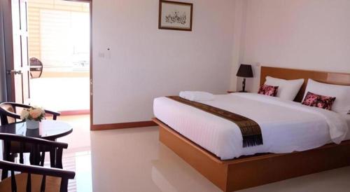 a bedroom with a large white bed and a table at Thatphanom View Hotel Nakhon in Nakhon Phanom