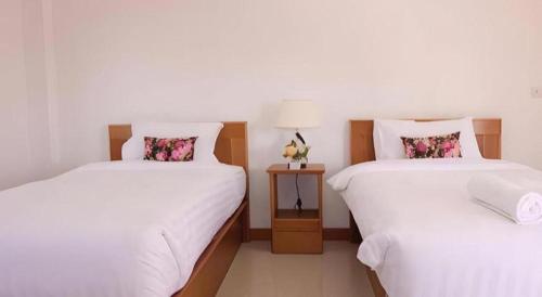 two beds in a room with white sheets and flowers at Thatphanom View Hotel Nakhon in Nakhon Phanom