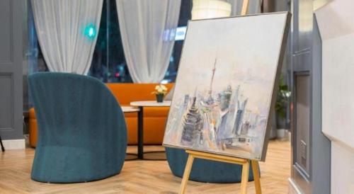 a painting on a easel next to a blue chair at Magnotel Shanghai Henglong Plaza in Shanghai