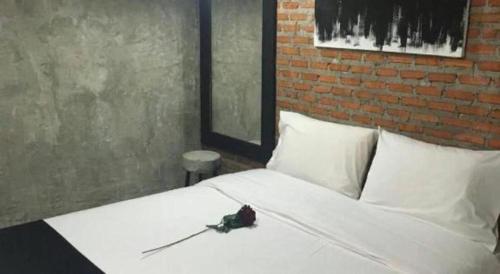 a bedroom with a white bed with a brick wall at 41Studio in Nakhon Phanom