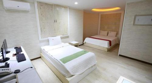 a hotel room with two beds and a desk and a desk at Hotel Primo Daejeon in Daejeon