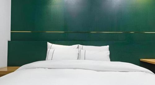 a bedroom with a large bed with a green wall at Hotel Primo Daejeon in Daejeon
