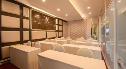a room with white tables and white chairs at Phuglong Hotel in Phayao