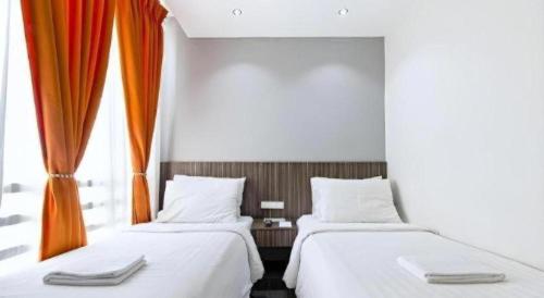 two beds in a room with an orange curtain at Eighty Eight Hotel in Koronadal