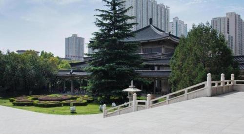 a building with a pine tree in a park at GreenTree Inn Xi'an Yanta District Dayanta Furongyuan Hotel in Xi'an