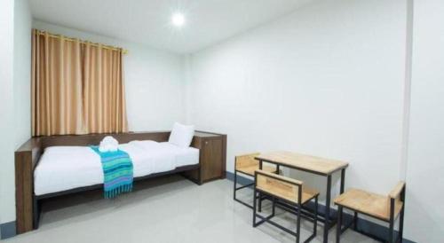 a bedroom with a bed and a table and chairs at Bees Smile Hotel in Chiang Rai