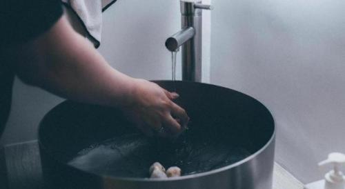 a person is washing a toilet in a bucket at SLEEEP HKG Causeway Bay in Hong Kong