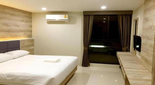 a bedroom with a white bed and a television at Sattahip 9 Boutique Hotel in Pattaya Central