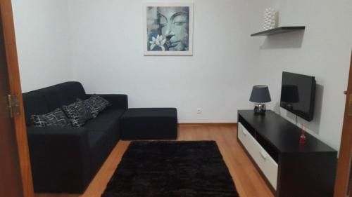 a living room with a black couch and a tv at Apartamento Moderno e Elegante in Ponta Delgada