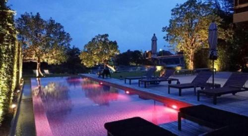 a swimming pool with benches and lights in a building at Phingphayla Photharam in Ratchaburi