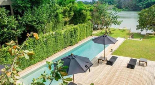 a swimming pool with two umbrellas and chairs and a swimming pool at Phingphayla Photharam in Ratchaburi