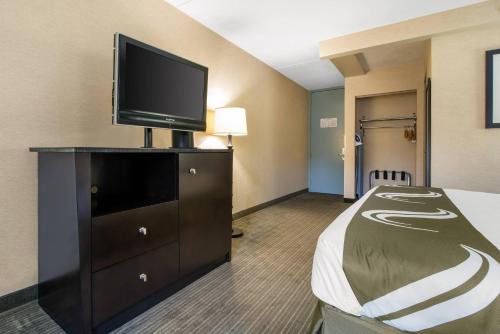 a hotel room with a bed and a flat screen tv at Quality Inn & Suites Charleston - Civic Center in Charleston