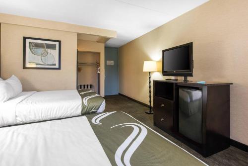 a hotel room with a bed and a flat screen tv at Quality Inn & Suites Charleston - Civic Center in Charleston