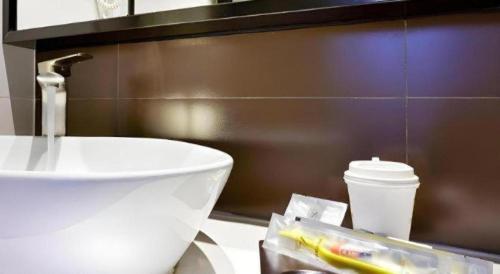 a bathroom with a sink and a toilet and a cup at 7 Days Premium Nanjing Gaochun Beiling Road Branch in Gaochun