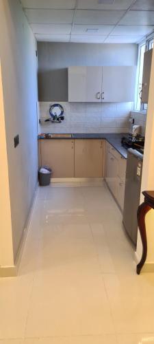 an empty room with a kitchen with white cabinets at Kimaya's Abode in Chandīgarh