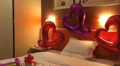 a bedroom with a bed with heart balloons on the wall at 7 Days Premium Nanjing Gaochun Beiling Road Branch in Gaochun