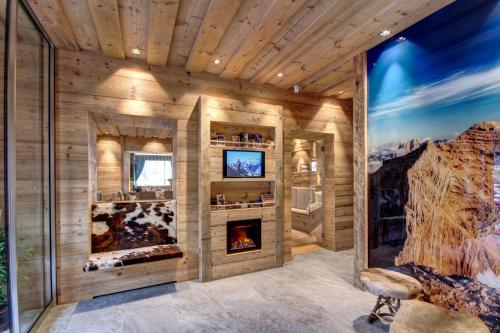 um quarto com uma lareira numa parede de madeira em Hotel Villa Alpina ***S em Cortina dʼAmpezzo