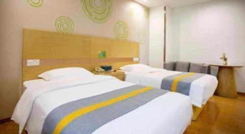 a hotel room with two beds with yellow and blue stripes at GreenTree Inn Shanghai National Convention and Exhibition Center Huaxiang Road in Shanghai