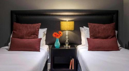two beds with red pillows and a vase of flowers at Oaks Queenstown Club Suites in Queenstown