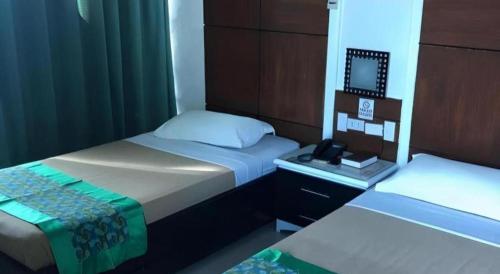 a bedroom with two beds and a mirror in it at Marcian Business Hotel in Zamboanga