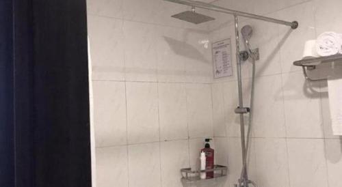 a shower in a bathroom with white tiles at New Moon Hotel in Hanoi