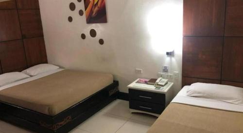 a bedroom with two beds and a night stand with a phone at Marcian Business Hotel in Zamboanga