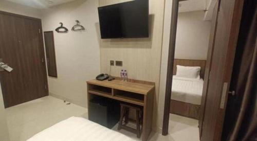 a bedroom with a desk with a bed and a television at WE Hotel Kowloon in Hong Kong