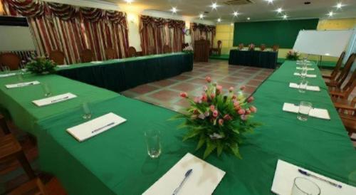 a long table with a green table cloth and flowers on it at Lucky Star Hotel in Phnom Penh