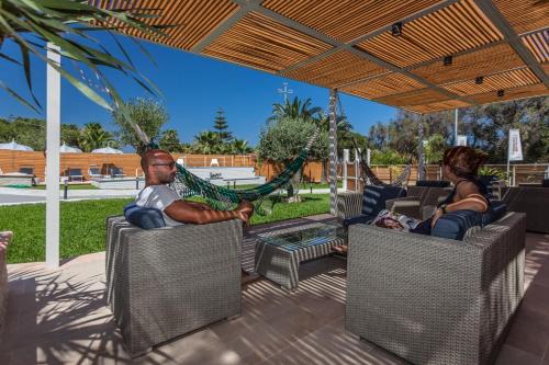 a man and a woman sitting in hammocks on a patio at Villa Sunset B&B/Apartments in Fontane Bianche