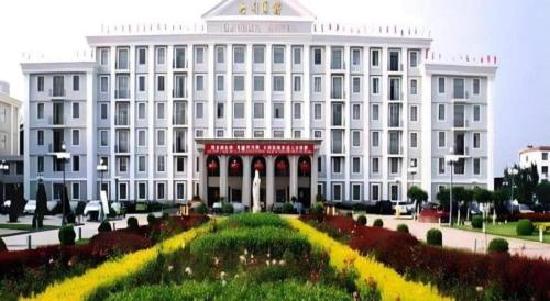 a large white building with a garden in front of it at Datong Hotel in Datong