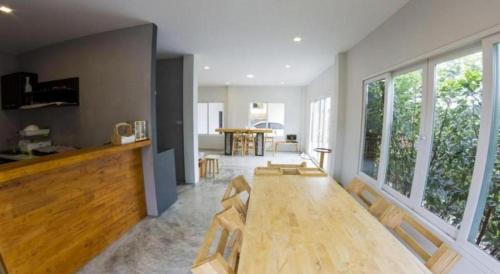 Una sala de estar con una mesa de madera y una gran ventana. en Maximize Brand New Hostel Udonthani, en Udon Thani