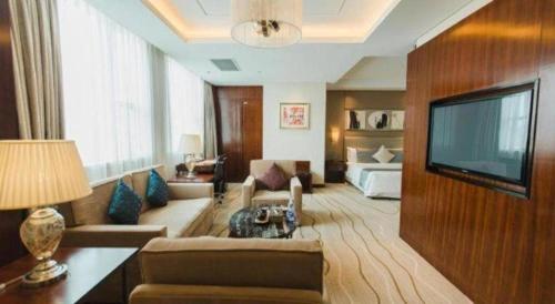 a living room with a couch and a television and a bed at Grand Soluxe Zhongyou Hotel Shenzhen in Shenzhen