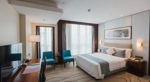 a hotel room with a bed and a desk and a television at Grand Soluxe Zhongyou Hotel Shenzhen in Shenzhen