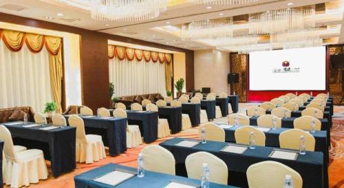 a conference room with tables and chairs and a screen at Grand Soluxe Zhongyou Hotel Shenzhen in Shenzhen