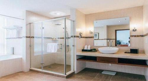 a bathroom with a glass shower and a sink at Grand Soluxe Zhongyou Hotel Shenzhen in Shenzhen