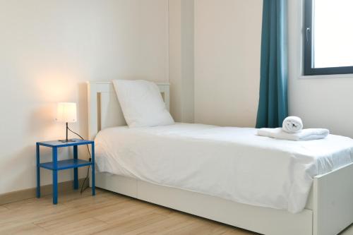 a small bedroom with a white bed and a blue night stand at La Pépinière -Parking Barbecue- 6P in Saint-Pierre-dʼAlbigny