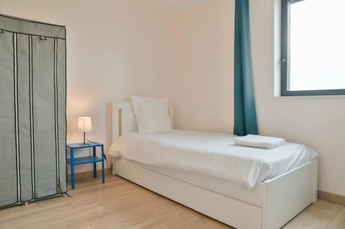 a white bedroom with a bed and a blue nightstand at La Pépinière -Parking Barbecue- 6P in Saint-Pierre-dʼAlbigny