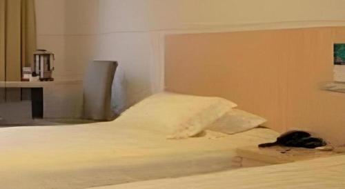 a cat laying on a bed in a room at Jinjiang Inn Wenzhou Shuangyu The Terminal in Wenzhou