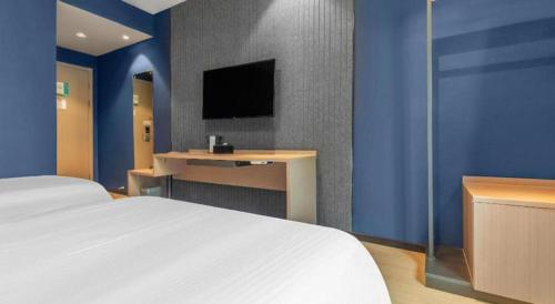 a bedroom with a bed and a desk and a tv at Jinjiang Inn Wenzhou Shuangyu The Terminal in Wenzhou
