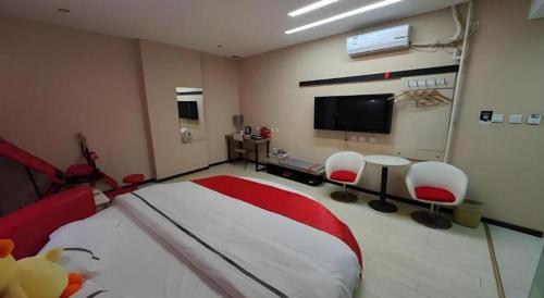 a bedroom with a bed and two chairs and a flat screen tv at Thank Inn Hotel He'nan Xinxiang Changyuan Bo'ai Road in Changyuan