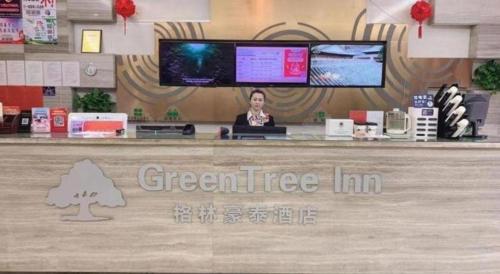a woman sitting at a counter in a store at GreenTree Inn Langfang GuAn County Xinyuan Street Express Hotel in Langfang