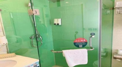a green bathroom with a shower and a sink at GreenTree Inn Langfang GuAn County Xinyuan Street Express Hotel in Langfang