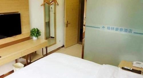 a bedroom with a bed and a tv and a mirror at GreenTree Inn Langfang GuAn County Xinyuan Street Express Hotel in Langfang