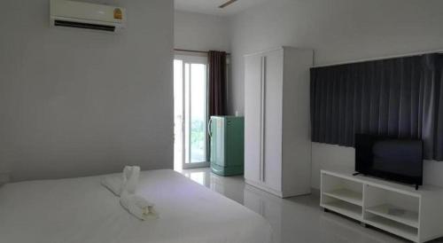 a white room with a bed and a television at River Residence Saraburi Hotel in Sara Buri