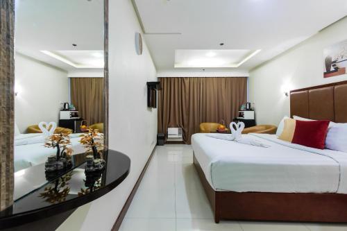 a hotel room with two beds and a mirror at JMM Grand Suites in Manila