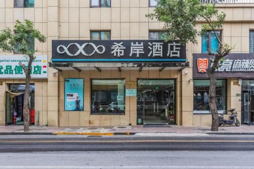 a building with a sign on the side of a street at Xana Hotelle· Tianjin Railway Station Jinwan Square Binjiang Avenue in Tianjin
