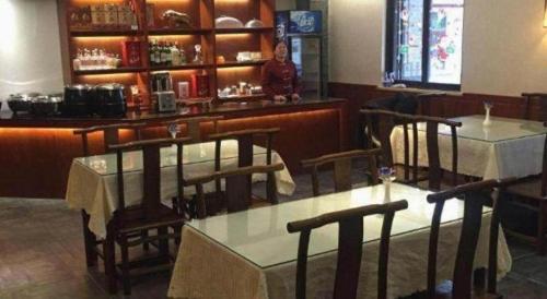 a restaurant with two tables and a woman at a bar at James Joyce Coffetel Xian Dayanta Metro Station Branch in Xi'an